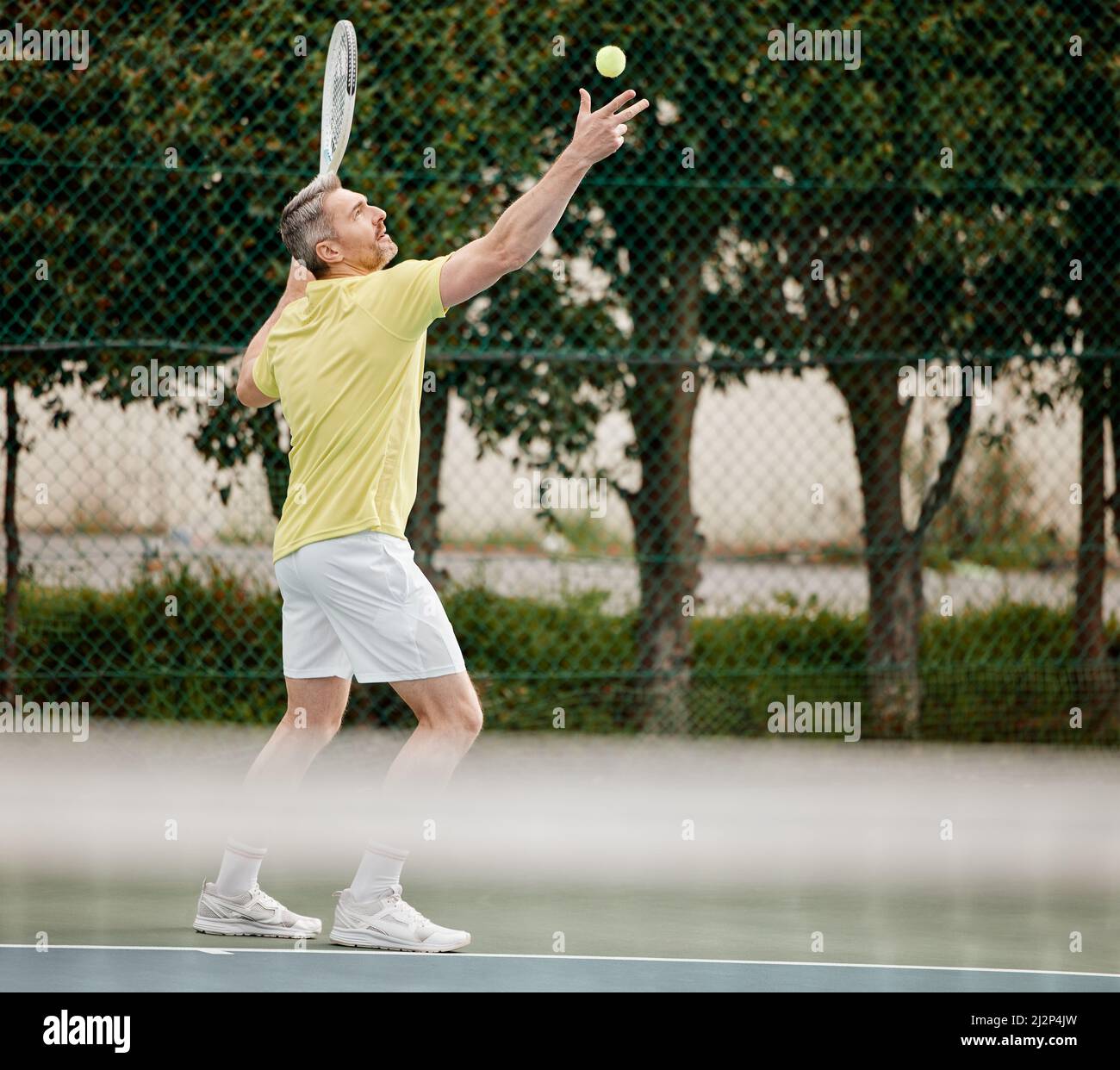 Iniziamo. Sparo a tutta lunghezza di un bel giocatore di tennis maschile maturo che serviva durante la sua partita. Foto Stock