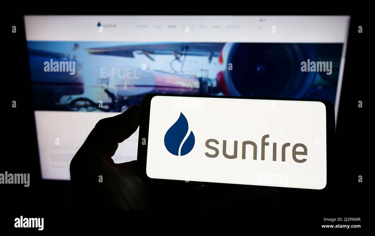 Persona che detiene il cellulare con il logo della società tedesca di energia rinnovabile Sunfire GmbH sullo schermo di fronte alla pagina web. Mettere a fuoco sul display del telefono. Foto Stock