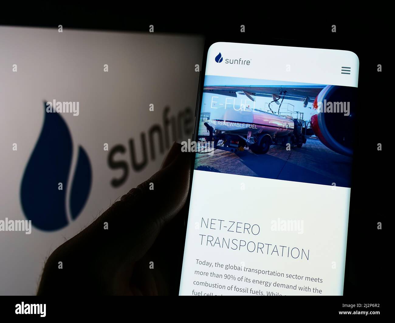 Persona che detiene il cellulare con il sito web della società tedesca di energia rinnovabile Sunfire GmbH sullo schermo di fronte al logo. Concentrarsi sul centro del display del telefono. Foto Stock