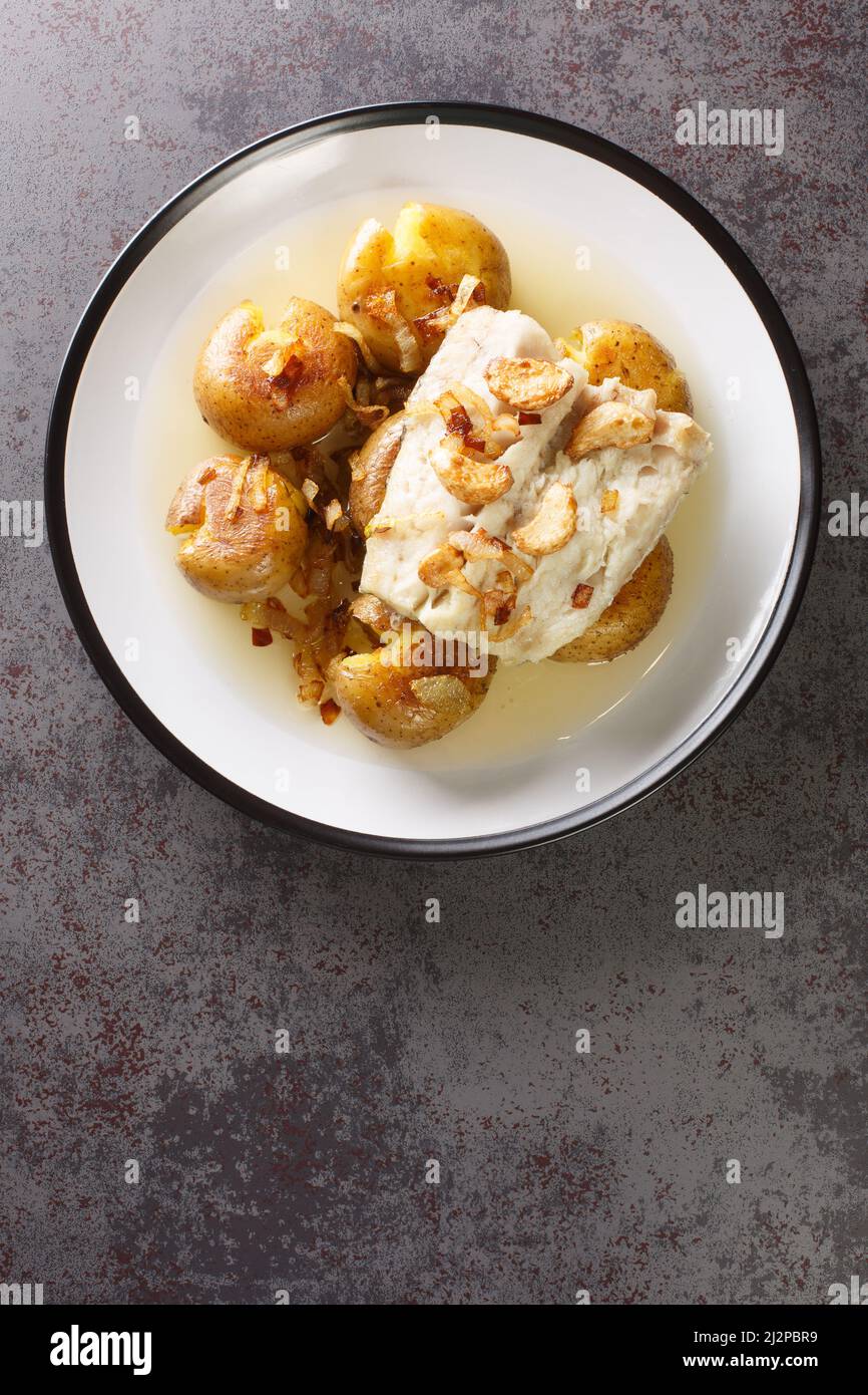 Bacalhau a Lagareiro Cod alla griglia salato con olio d'oliva servito con  patate al forno primo piano nel piatto sul tavolo. Vista dall'alto  verticale Foto stock - Alamy