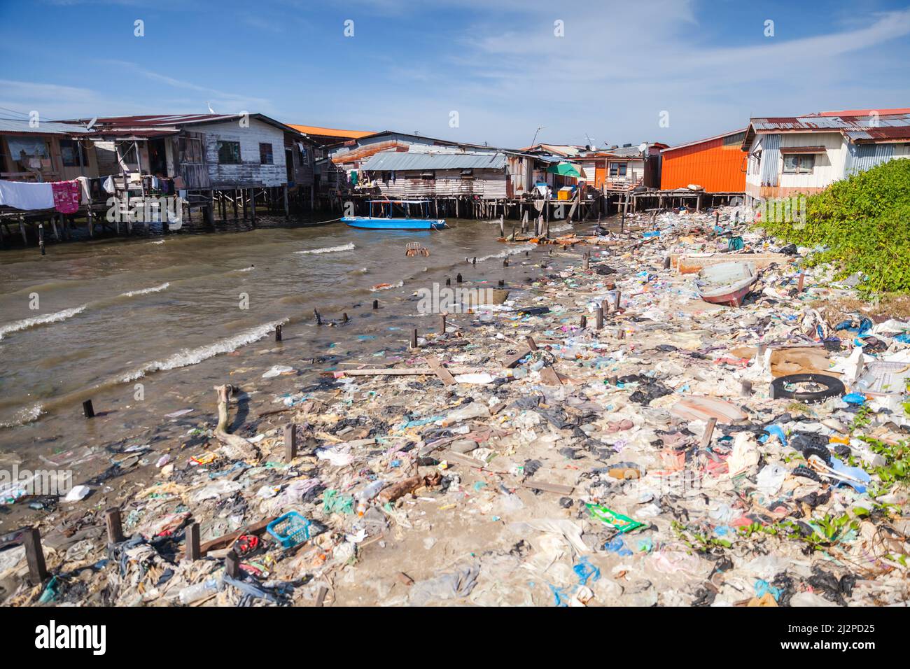 Kota Kinabalu, Malesia - 17 marzo 2019: Spazzatura costiera con case in legno e ponti pedonali su palafitte su sfondo. Povero distretto costiero di Kota Ki Foto Stock