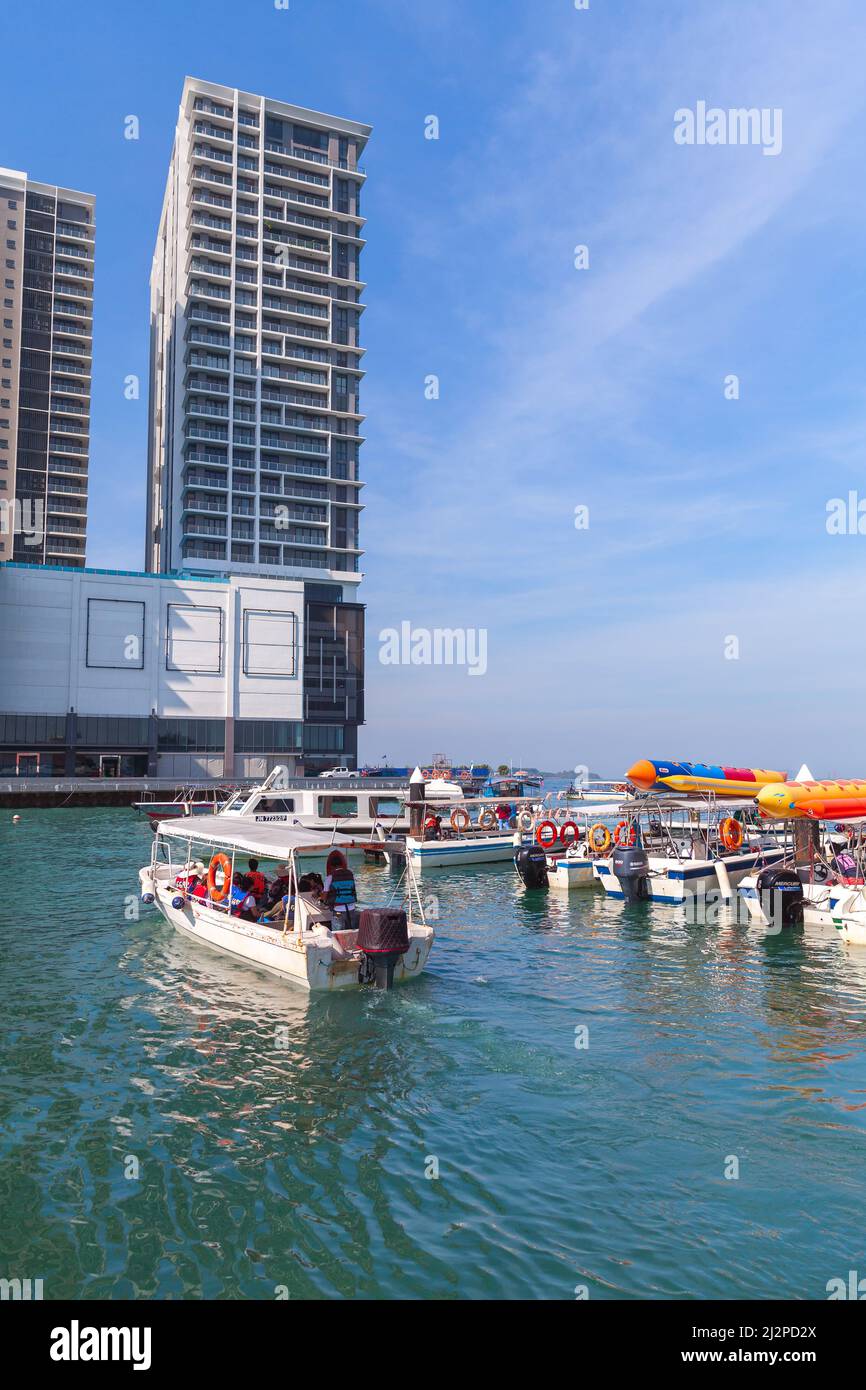 Kota Kinabalu, Malesia - 17 marzo 2019: Barche a motore bianche con passeggeri sono vicino al terminal dei traghetti di Jesselton Point in una giornata di sole, foto verticale Foto Stock