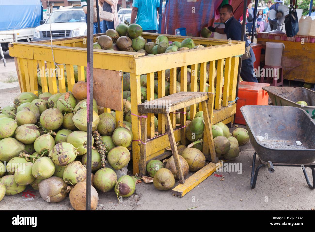 Kota Kinabalu, Malesia - 23 marzo 2019: Mercato Kota Kinabalu, noci di cocco in vendita sono in contenitore di legno giallo, venditore locale è nelle vicinanze Foto Stock