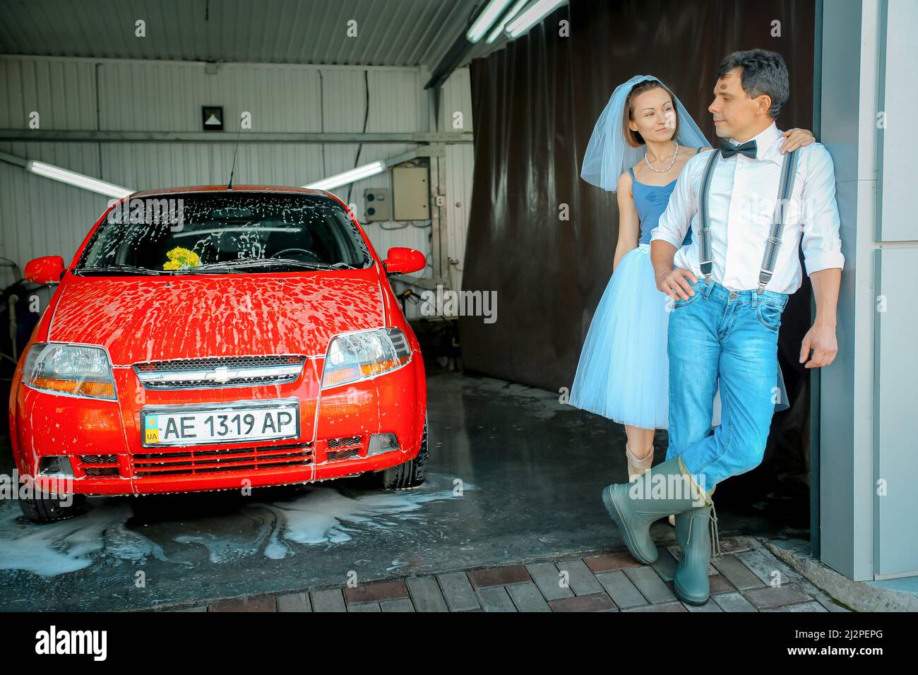 Dnepropetrovsk, Ucraina - 09.11.2016: Ritratto di una giovane coppia in abito da sposa che celebra il loro anniversario di matrimonio. La coppia sta lavando il ca Foto Stock
