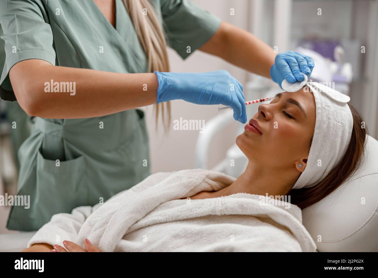 Beautician professionale che fa le iniezioni, riempiendo la faccia femminile con acido ialuronico Foto Stock