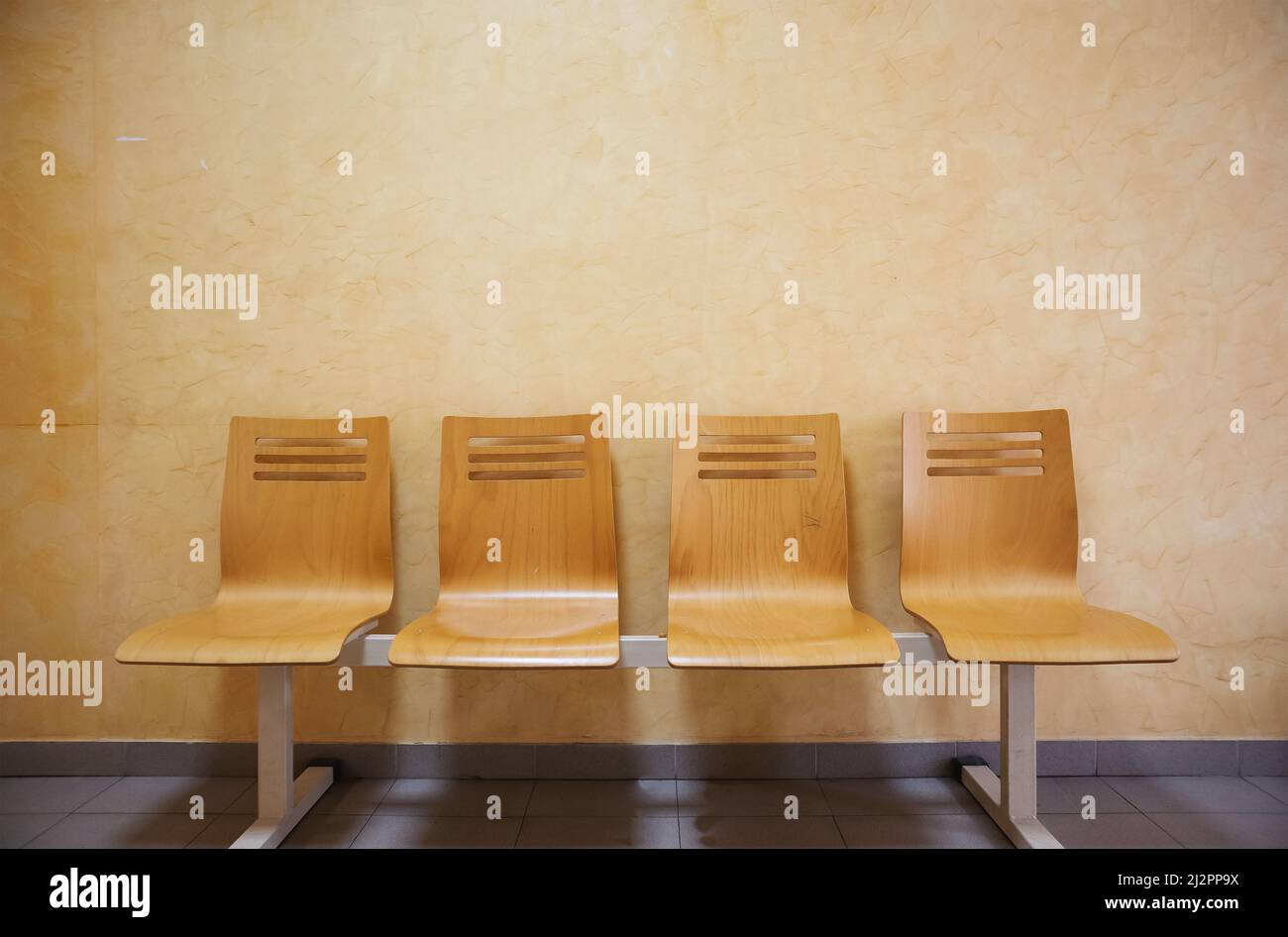 Sedie vuote di legno davanti al muro, parte della sala d'attesa. Foto Stock