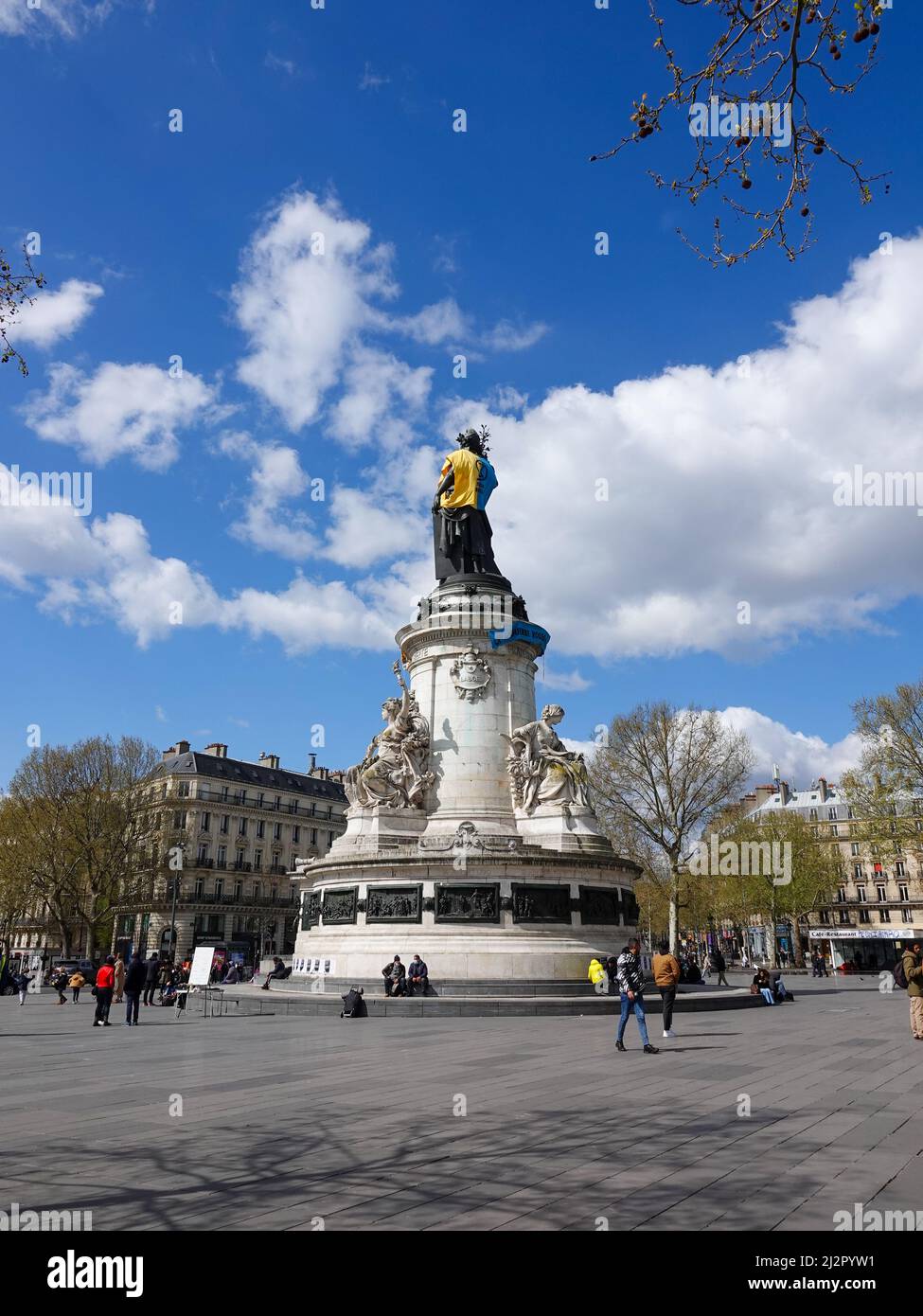 Monumento alla Repubblica, adornato con un gilet giallo e blu nei colori della bandiera Ucraina, insieme con il simbolo della ribellione di estinzione, movimento internazionale sociale ambientale, in protesta della guerra in Ucraina e l'uso eccessivo di petrolio e il suo ruolo nella distruzione del clima. 2 aprile 2022, Parigi, Francia Foto Stock