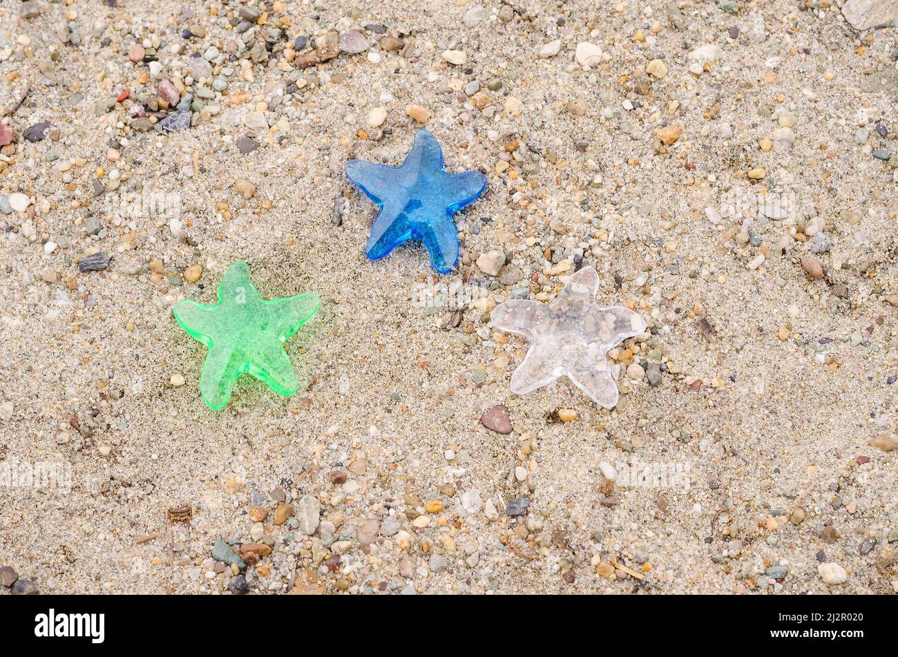 Tre stelle decorative su uno sfondo di sabbia da spiaggia con uno spazio copia, il concetto di una vacanza in un hotel a tre stelle Foto Stock