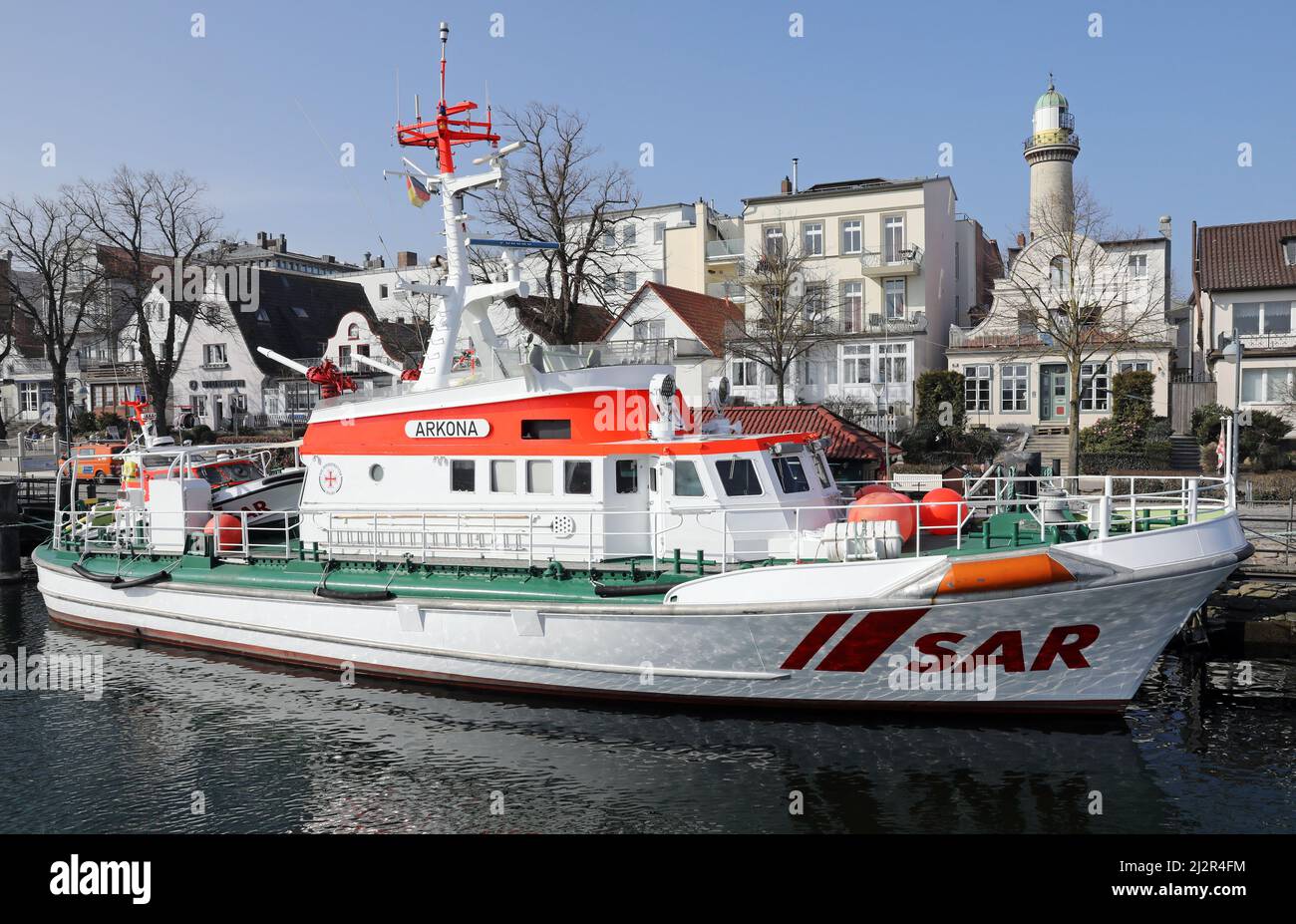 25 marzo 2022, Meclemburgo-Pomerania occidentale, Warnemünde: L'incrociatore di salvataggio 'Arkona' nel Vecchio torrente della località del Mar Baltico, sullo sfondo il faro. Foto: Bernd Wüstneck/dpa-Zentralbild/ZB Foto Stock