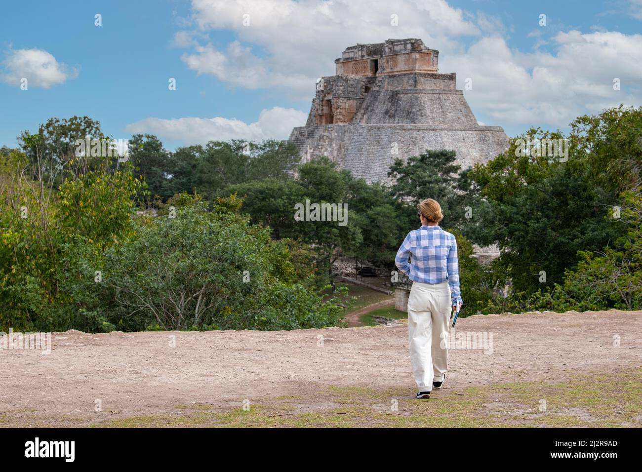 Giovane donna che esplora antiche rovine maya presso il sito archeologico di Uxmal (Yucatan, Messico) di fronte alla famosa Piramide del Mago Foto Stock