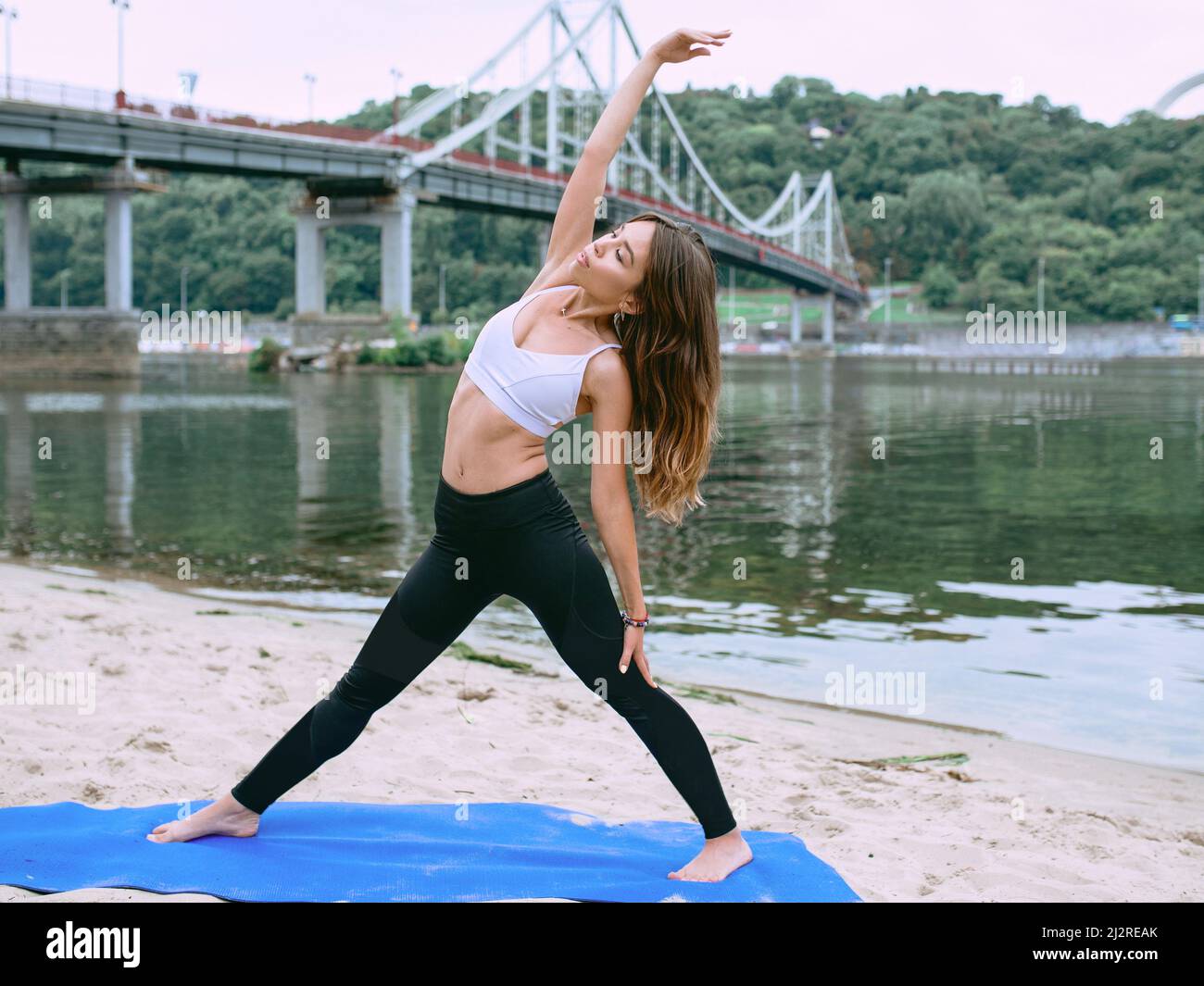 giovane donna in abbigliamento sportivo in diverse asana yoga all'aperto sulla spiaggia vicino al fiume. Yoga e concetto di sport Foto Stock