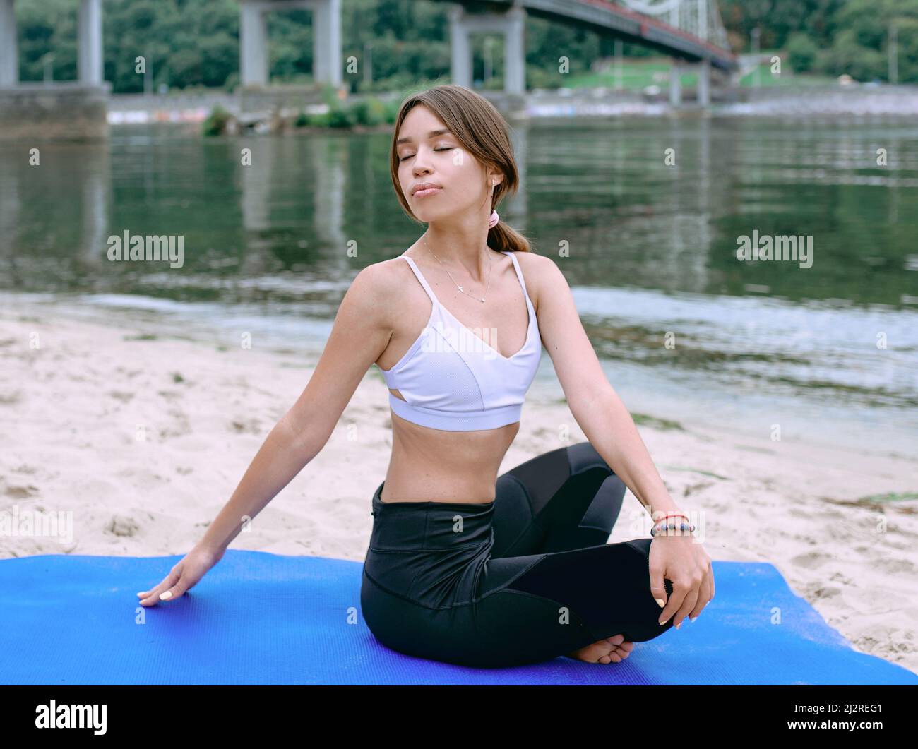 giovane donna in abbigliamento sportivo in diverse asana yoga all'aperto sulla spiaggia vicino al fiume. Yoga e concetto di sport Foto Stock