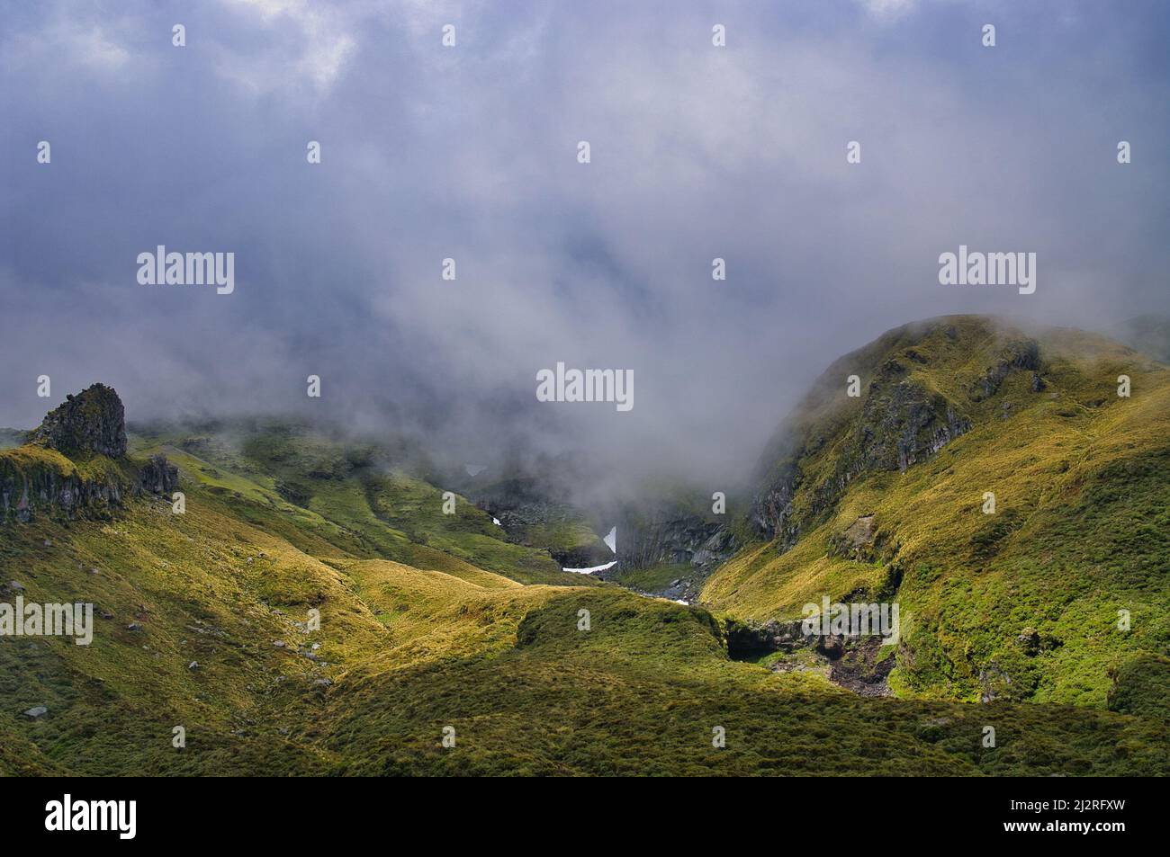 Le aspre gole alpine e le fessure del Castello di Humphries sul vulcano Monte Taranaki (Nuova Zelanda) avvolti da nuvole minacciose. Foto Stock