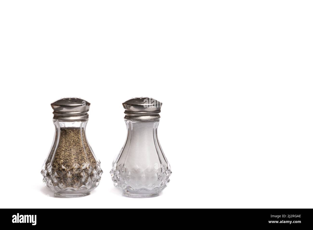 Agitatori con sale e pepe in vetro con coperchi in metallo argento su sfondo bianco con spazio di copia Foto Stock