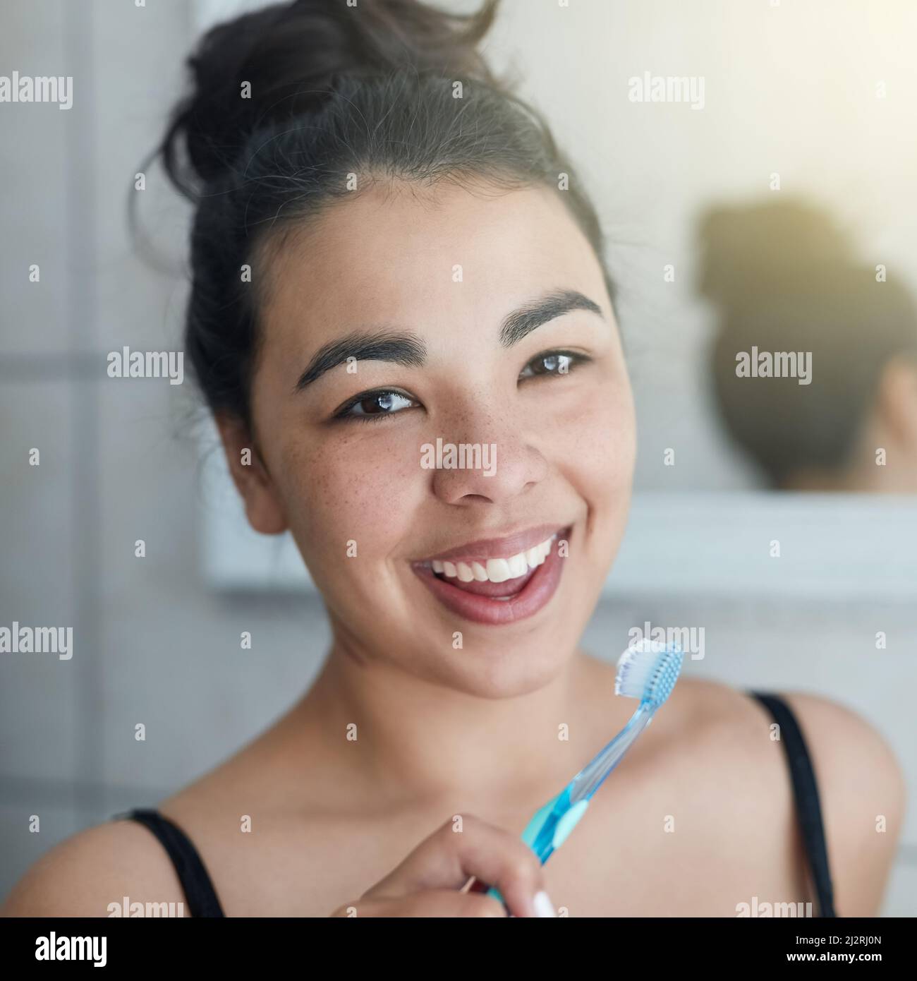 Mantenere le gengive e i denti sani. Ritratto di una bella giovane donna che le spazzolava i denti in bagno. Foto Stock