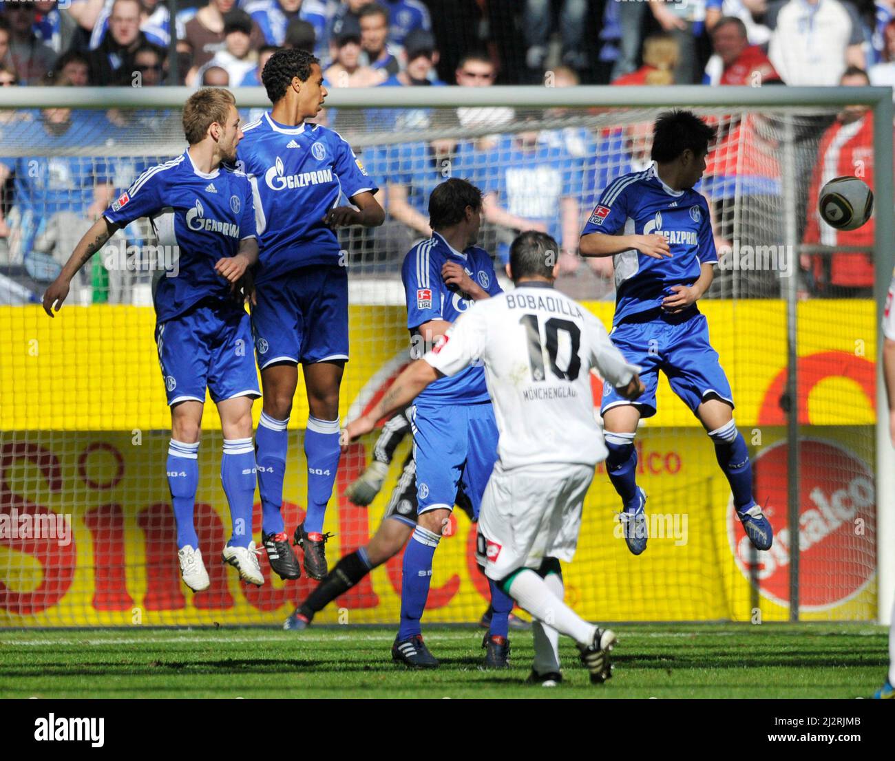 Veltins Arena Gelsenkirchen, Germania, 17,4.2010, Calcio: Bundesliga tedesca, stagione 2009/10, matchday 31, Schalke 04 (S04, blu) vs Borussia Moenchengladbach (BMG, bianco) — aul BOBADILLA, Moenchengladbach dà un calcio libero, giocatori di Schalke, da sinistra: Ivan Rakitic, Joel MATIP, Benedikt Hoewedes e Hao Junmin si prende cura della palla Foto Stock