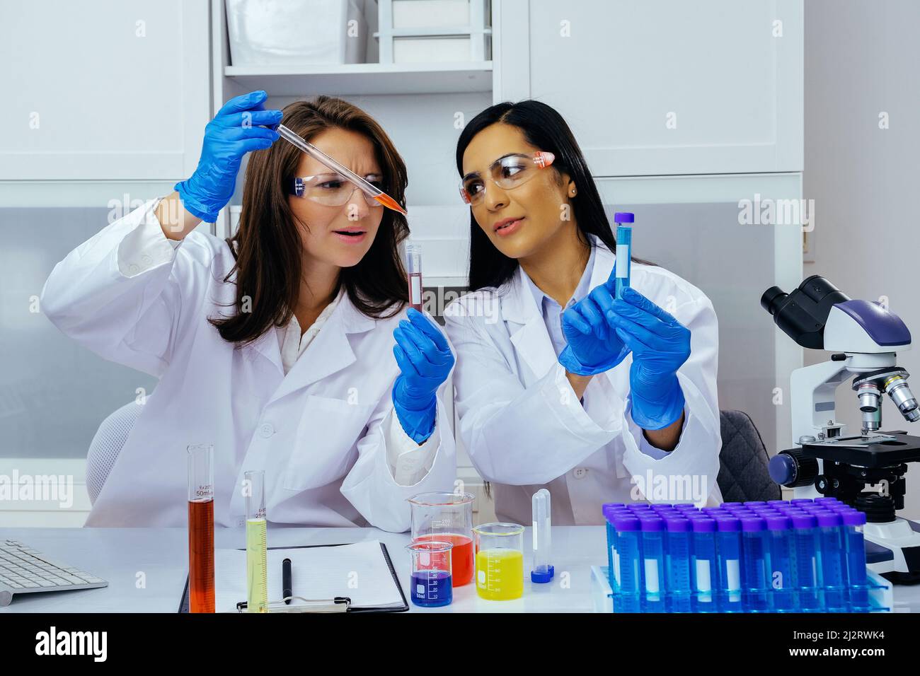 Due belle giovani scienziati femminili che lavorano in laboratorio con provette che fanno una certa ricerca industria farmaceutica Foto Stock