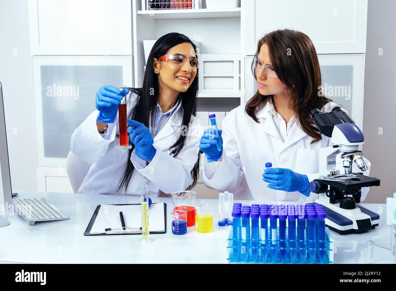 Due belle giovani scienziati femminili che lavorano in laboratorio con provette che fanno una certa ricerca industria farmaceutica Foto Stock