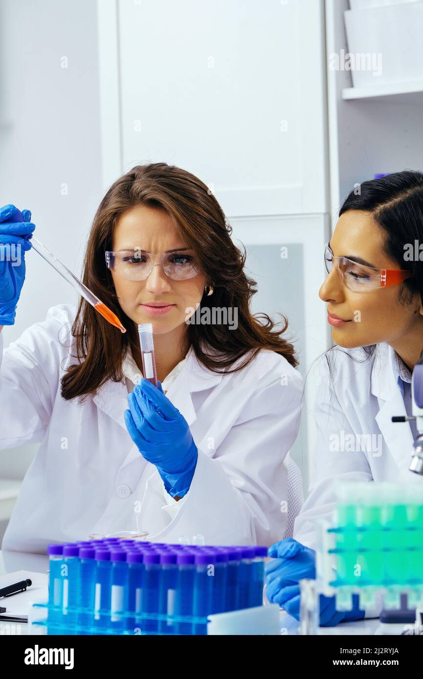 Due belle giovani scienziati femminili che lavorano in laboratorio con provette che fanno una certa ricerca farmaceutica Foto Stock