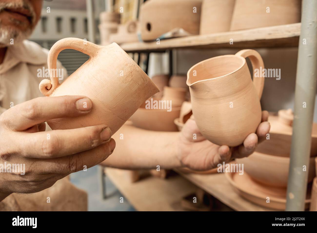 Artigiano della ceramica che controlla i vasi di argilla e organizza le mensole fino alla pittura finale. Artigianato fatto a mano in argilla. Foto Stock