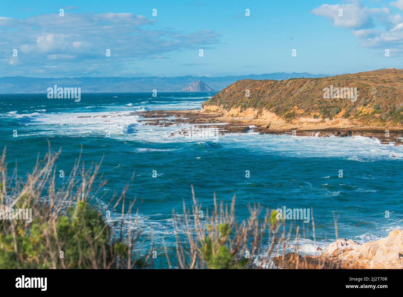 Condimento nei colori blu e turchese. Oceano Pacifico, scogliere rocciose e silhouette di Morro Rock. Vista dal parco statale del Montana del Oro, California coa Foto Stock
