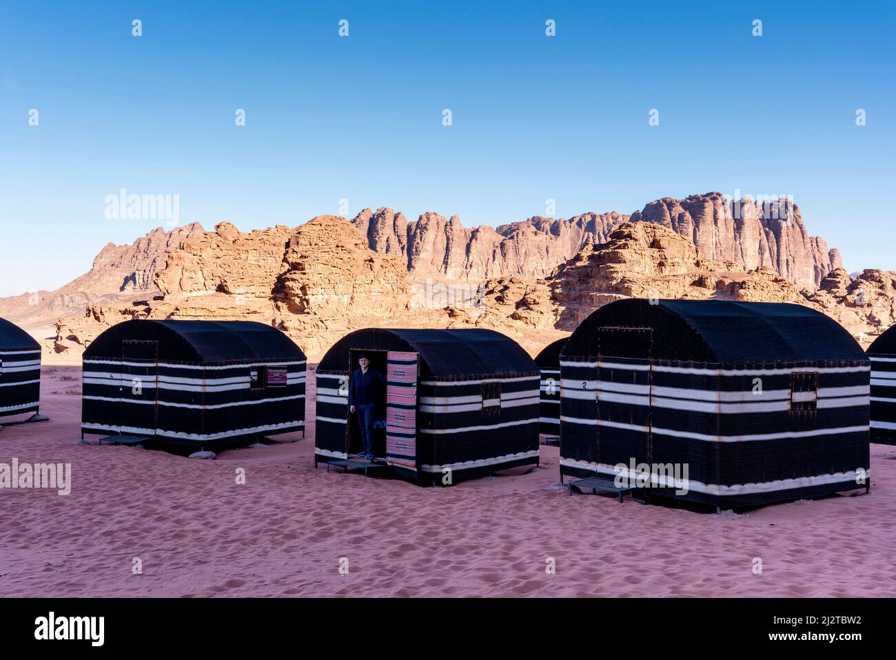 Un giovane uomo si erge alla porta di Una tenda beduina nel deserto di Wadi Rum, Giordania, Asia. Foto Stock