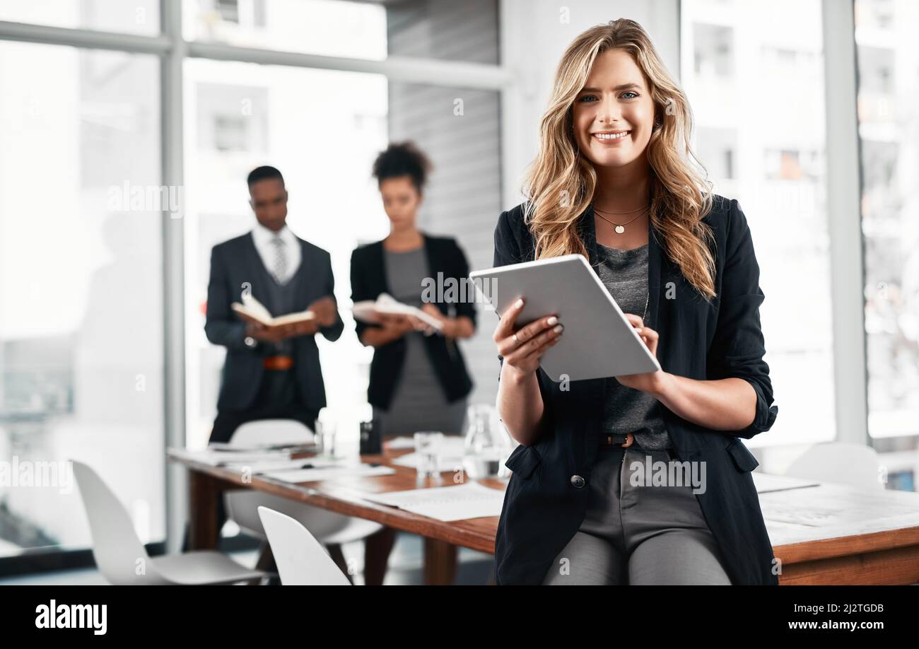 Mi aiuta a scoprire le lacune del mercato su cui capitalizzare. Ritratto di una giovane donna d'affari che usa un tablet digitale in ufficio con i suoi colleghi Foto Stock