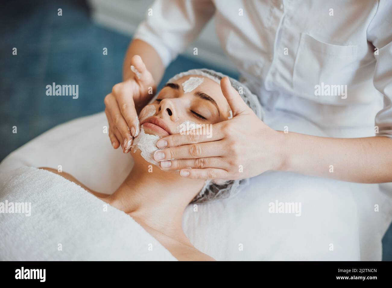 Bella donna che riceve massaggio viso e trattamento spa al salone di bellezza. Cosmetologia procedura di bellezza. Cura della pelle del viso. Trattamento viso. Giovane Foto Stock