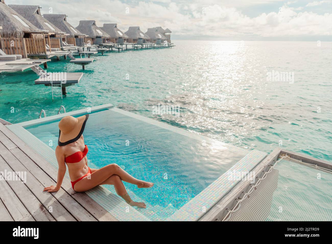 Vacanza di viaggio di lusso a Bora Bora high end resort hotel turista signora abbronzatura in bikini presso la piscina al overwater villa suite Foto Stock