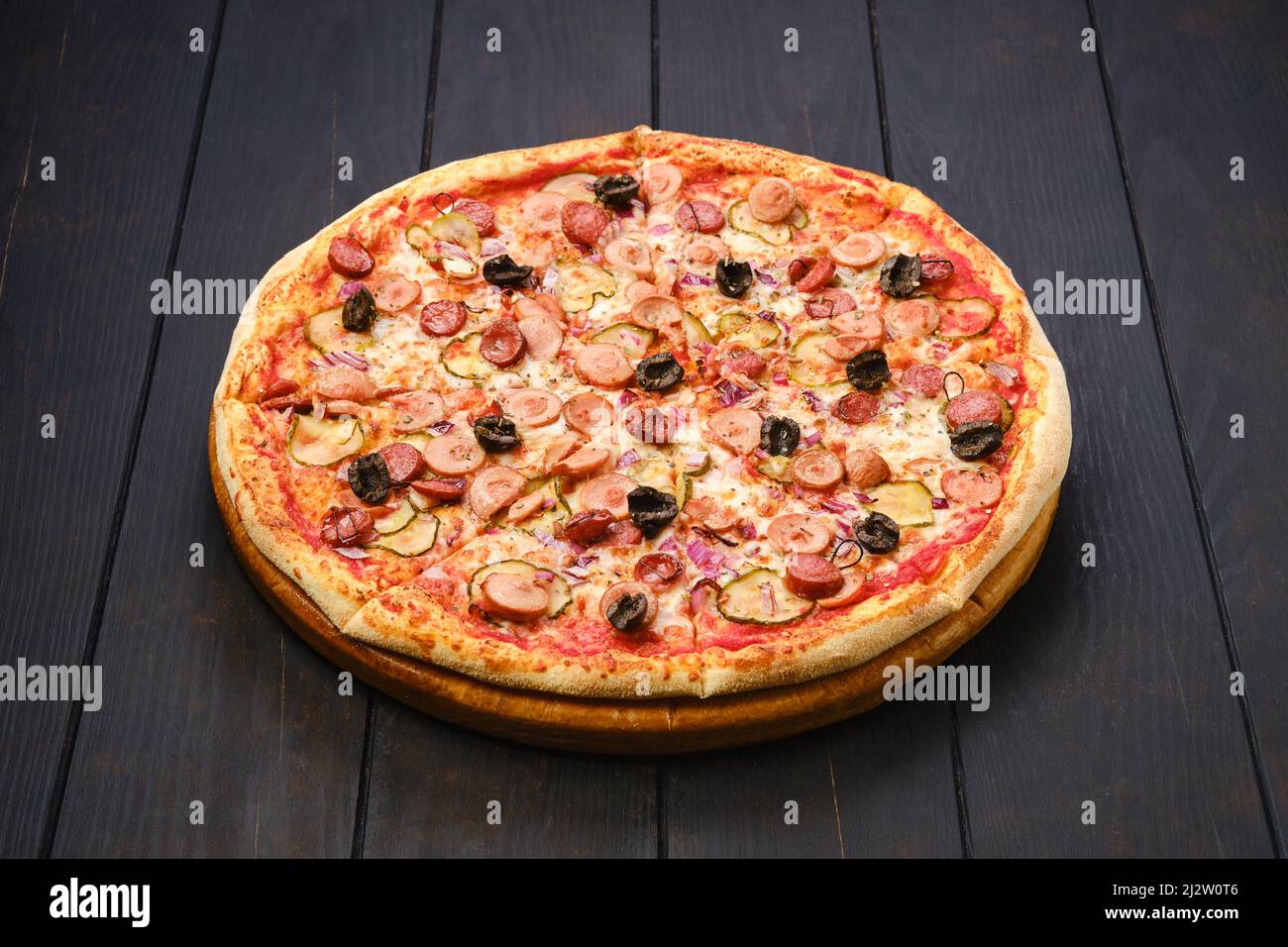 Pizza con vari tipi di salsicce sottili, cetrioli sottaceto, olive e cipolla rossa Foto Stock