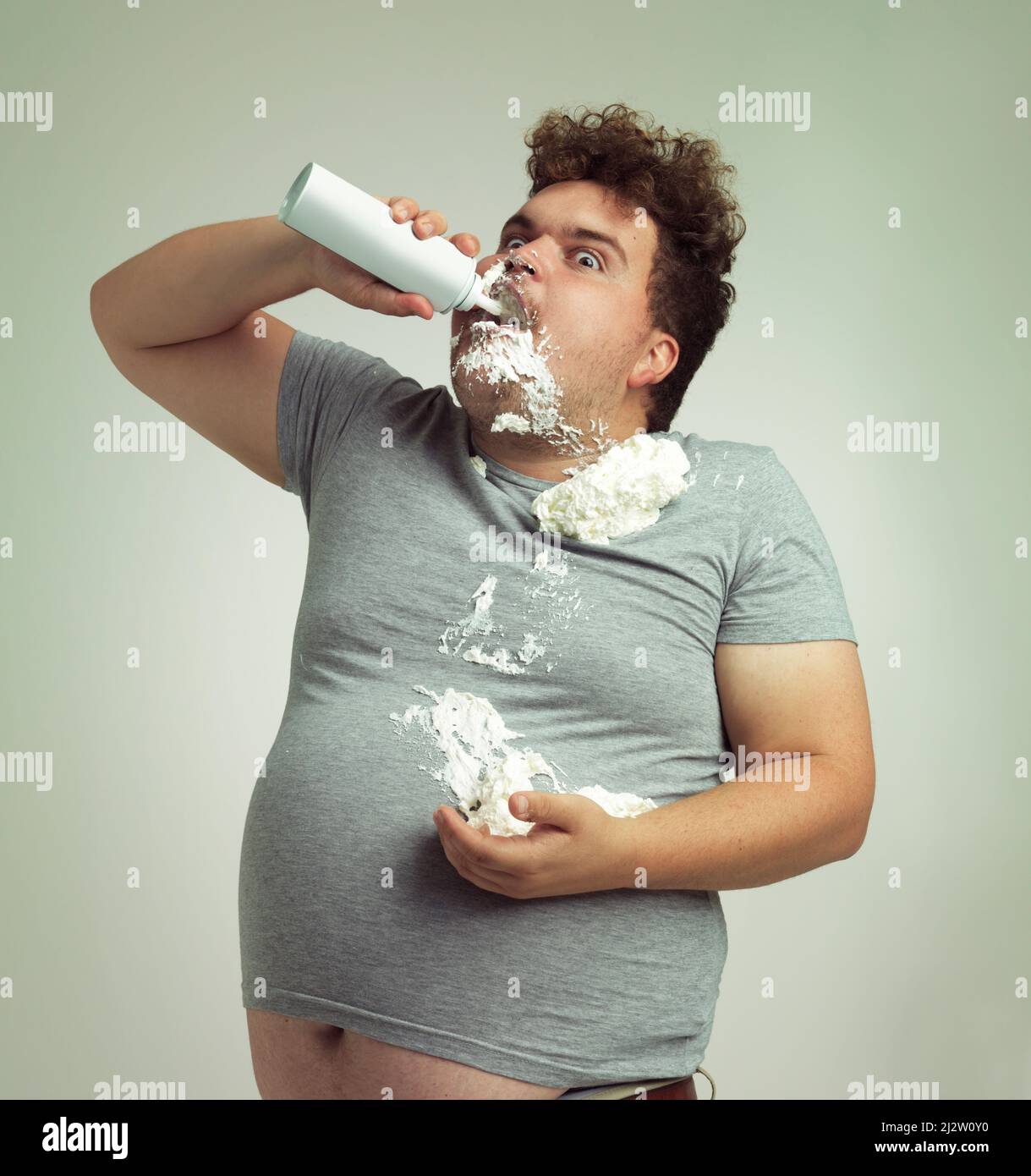 La mia dieta ha detto che devo mangiare gli alimenti leggeri. Shot di un uomo in sovrappeso che riempe la bocca con panna montata. Foto Stock