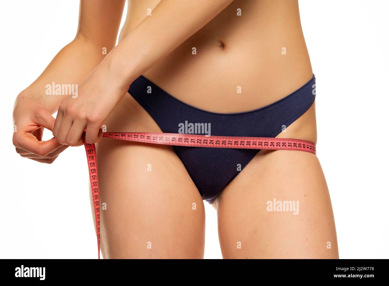 La giovane donna misura il suo luppolo con nastro di misurazione su sfondo bianco Foto Stock