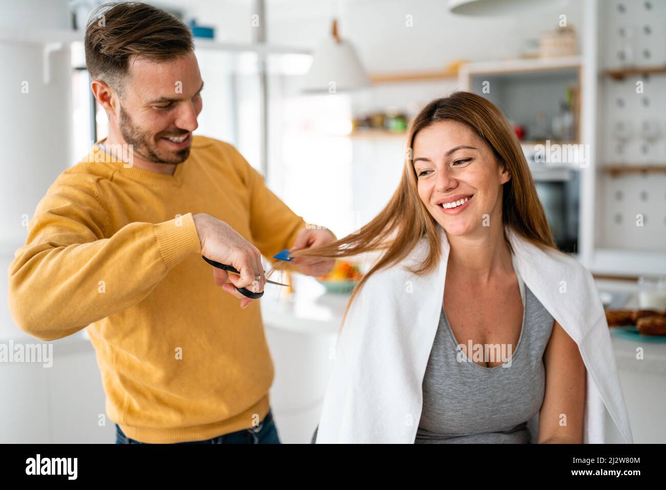 Coppia che ha i capelli tagliati a casa durante la quarantena coronavirus pandemico, online parrucchiere su tablet Foto Stock