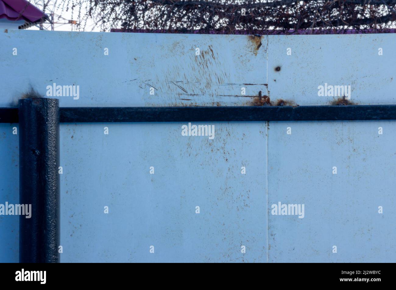 Recinzione grigia con elementi di ruggine e disegni. Foto Stock