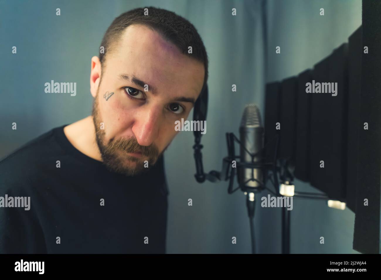 Primo piano ritratto di un creatore di musica rap caucasica guardando fotocamera con atteggiamento aggressivo mentre si alza in uno studio e registrare il suo nuovo album. Foto di alta qualità Foto Stock