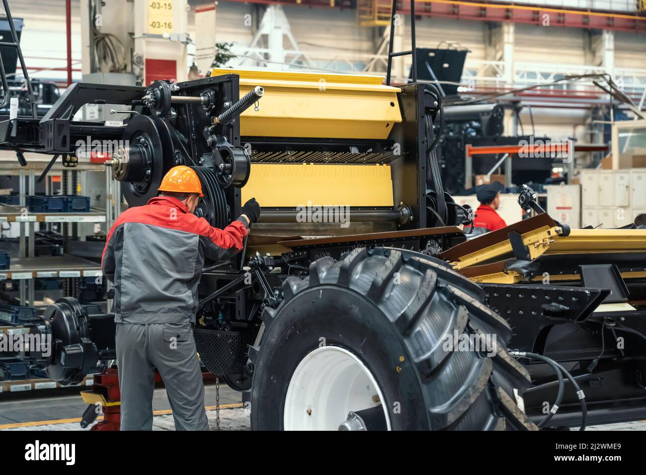 L'operatore monta la mietitrebbia per veicoli agricoli in un'officina industriale. Foto Stock