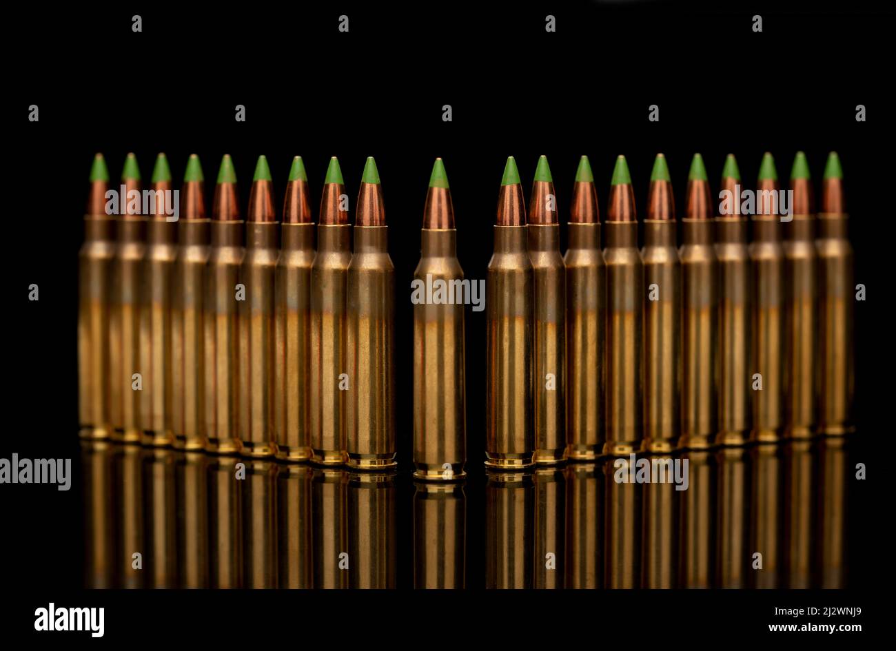 Un gruppo di 5,56 pallottole con punta verde e calibro ordinate nella riga su sfondo nero Foto Stock