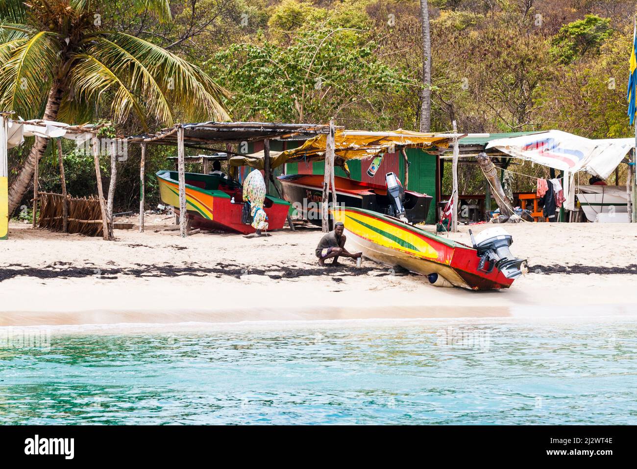 Spiaggia ombra e barche colorate, Caribbean Beach e vista a Salt Whistle Bay, Mayreau, Saint Vincent e Grenadine. Foto Stock