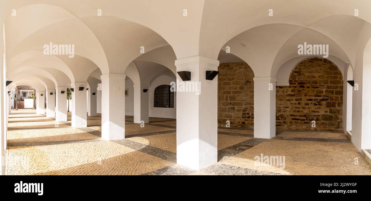 Olivenza, Spagna - 27 marzo 2022: Portico dipinto di bianco con molti archi e pavimento in pietra a motivi geometrici Foto Stock