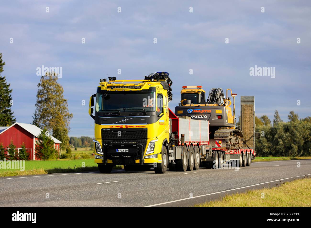 Volvo FH autocarro giallo personalizzato di Kankareen Paalutus Oy trasporta l'escavatore Volvo in una serata autunnale soleggiata. Loimaa, Finlandia. Settembre 18, 2020. Foto Stock