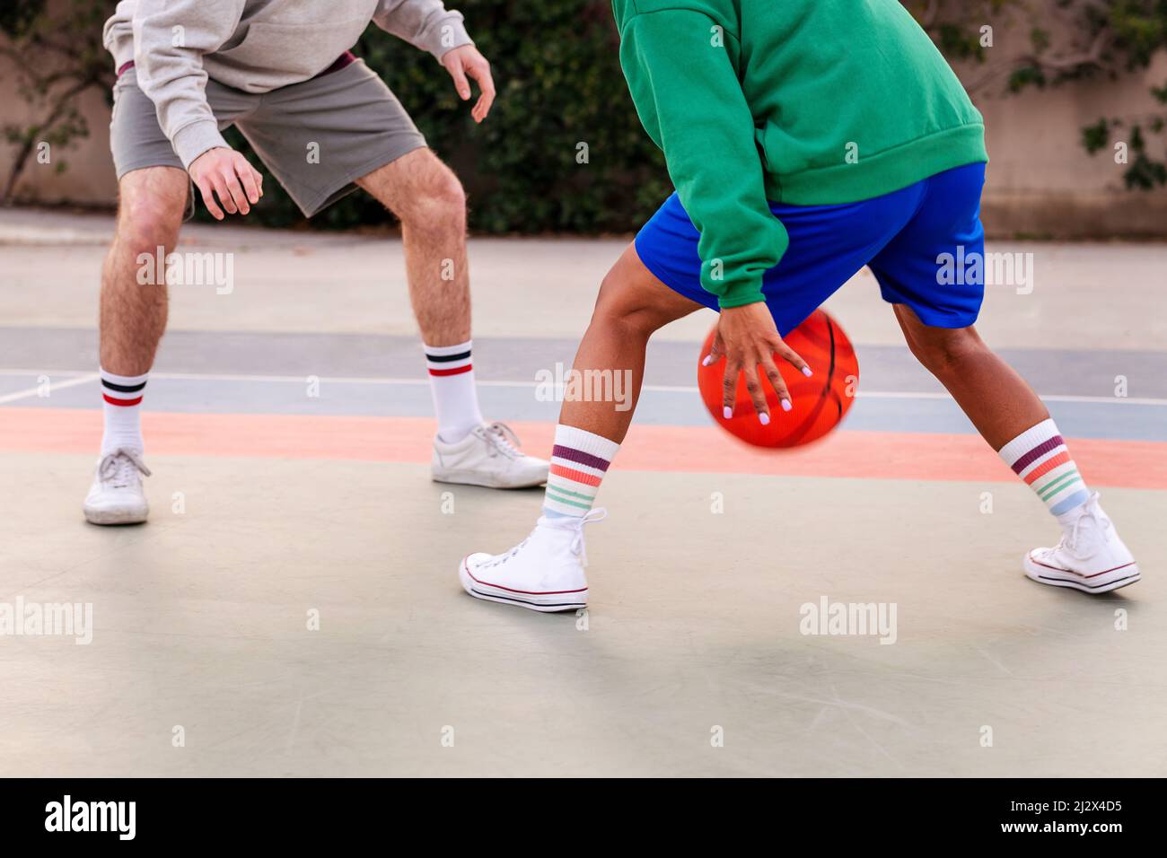 gambe di due amici irriconoscibili che giocano a basket su un campo cittadino, concetto di sport urbano in strada Foto Stock
