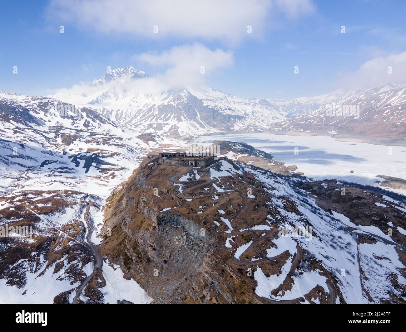 vista aerea del drone di antiche rovine fortilizio in montagna vicino al lago ghiacciato e diga Foto Stock