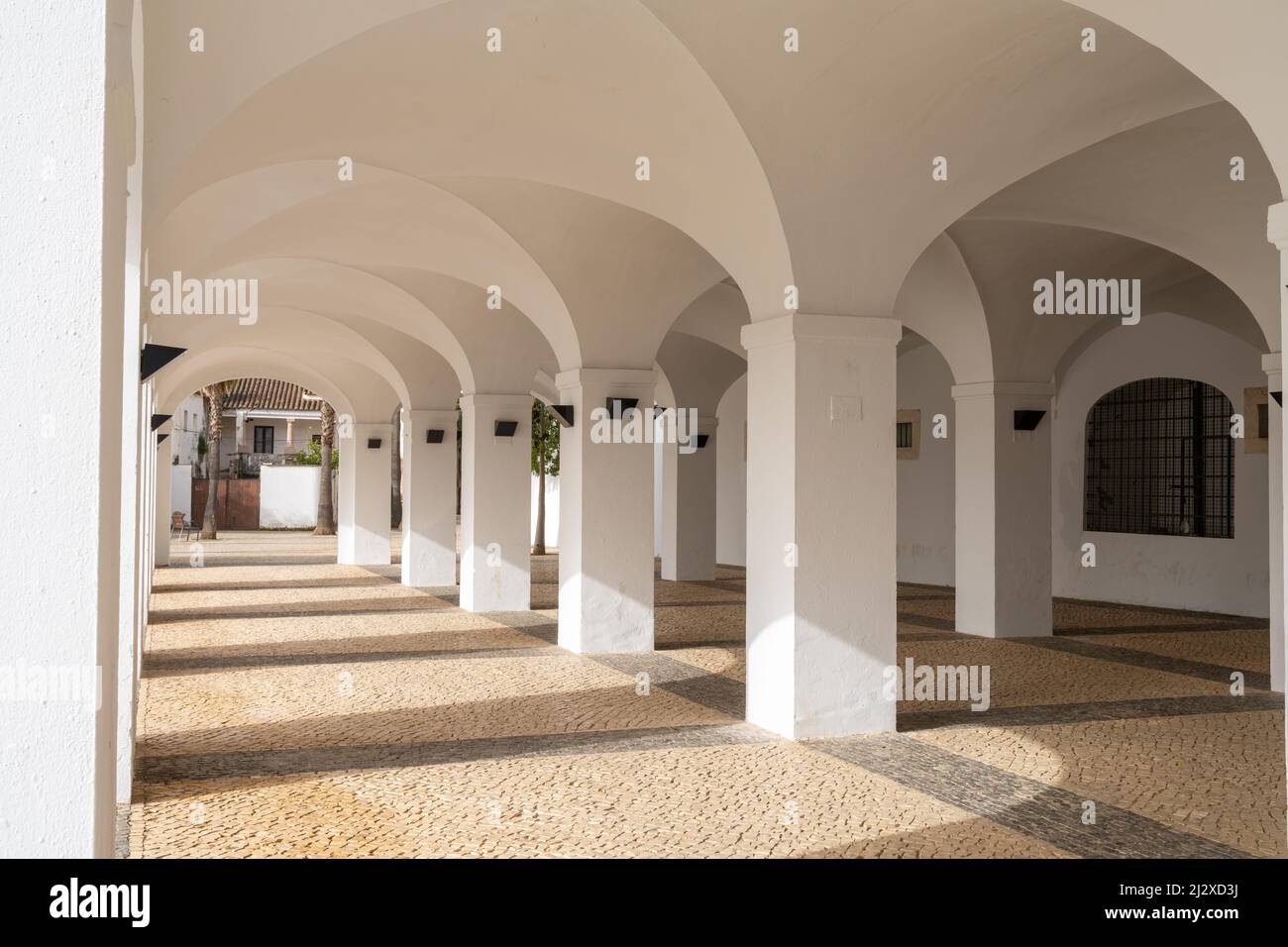 Olivenza, Spagna - 27 marzo 2022: Portico dipinto di bianco con molti archi e pavimento in pietra a motivi geometrici Foto Stock