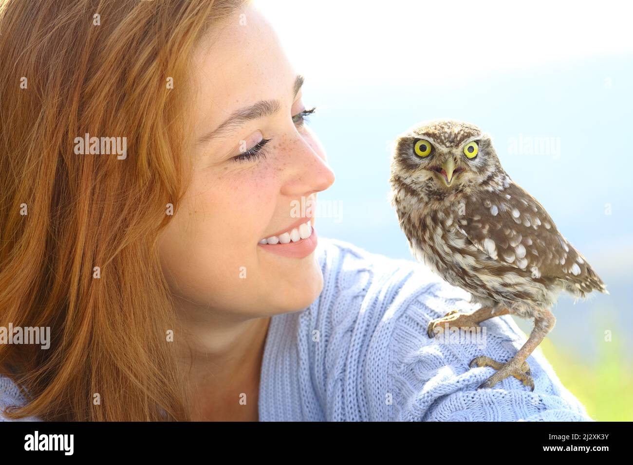 Donna felice con un owlet sulla spalla lo guarda in natura Foto Stock