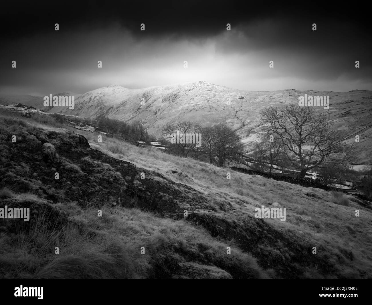 Le vette di Ill Bell e giogo sopra la valle di Trout Beck da Nanny Lane a fine inverno nel Lake District National Park, Cumbria, Inghilterra. Foto Stock