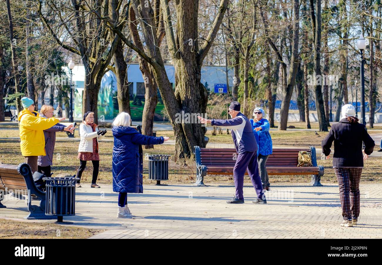 Minsk, Bielorussia - 25 marzo 2022: Un gruppo di persone anziane che fanno esercizi respiratori nel parco in una giornata di sole Foto Stock
