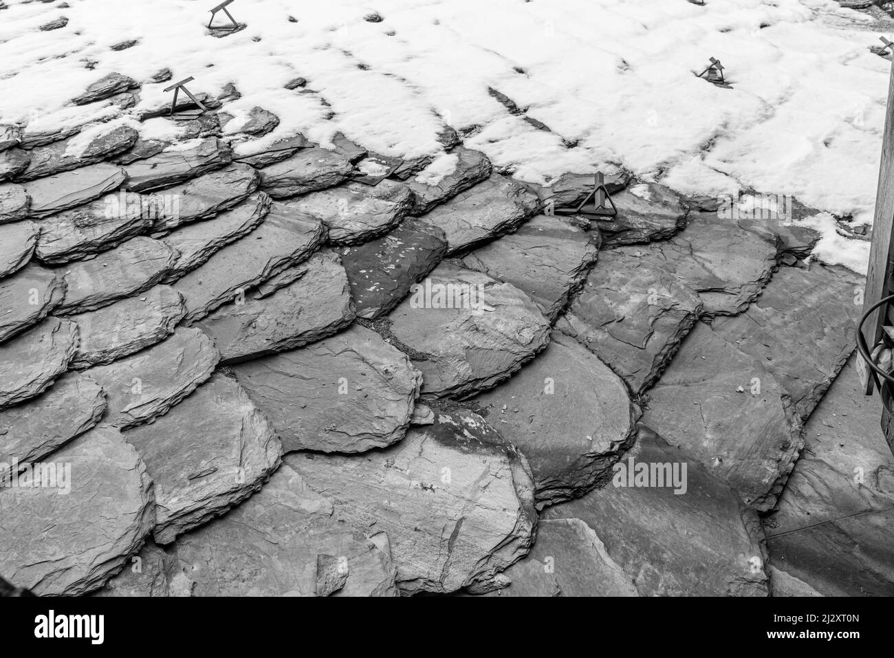 Vecchie tegole grigie, parzialmente ricoperte di neve, sfondo, monocromatiche, bianco e nero. Foto Stock
