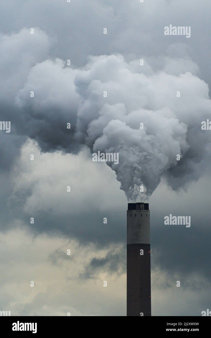 Primo piano di un alto camino stack in una centrale elettrica a carbone che pompano fumo e emissioni di inquinamento in alto nell'atmosfera con spazio copia Foto Stock