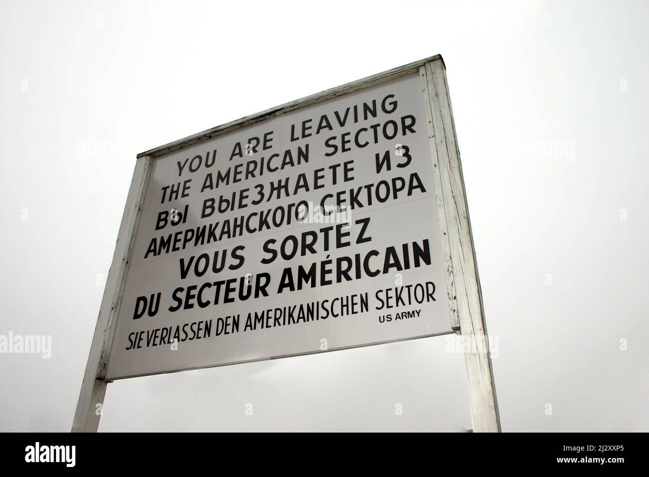 Checkpoint Charlie, Berlino, Germania. Il cartello al famoso incrocio del Muro di Berlino durante la Guerra fredda, posto contro un cielo grigio. Foto Stock