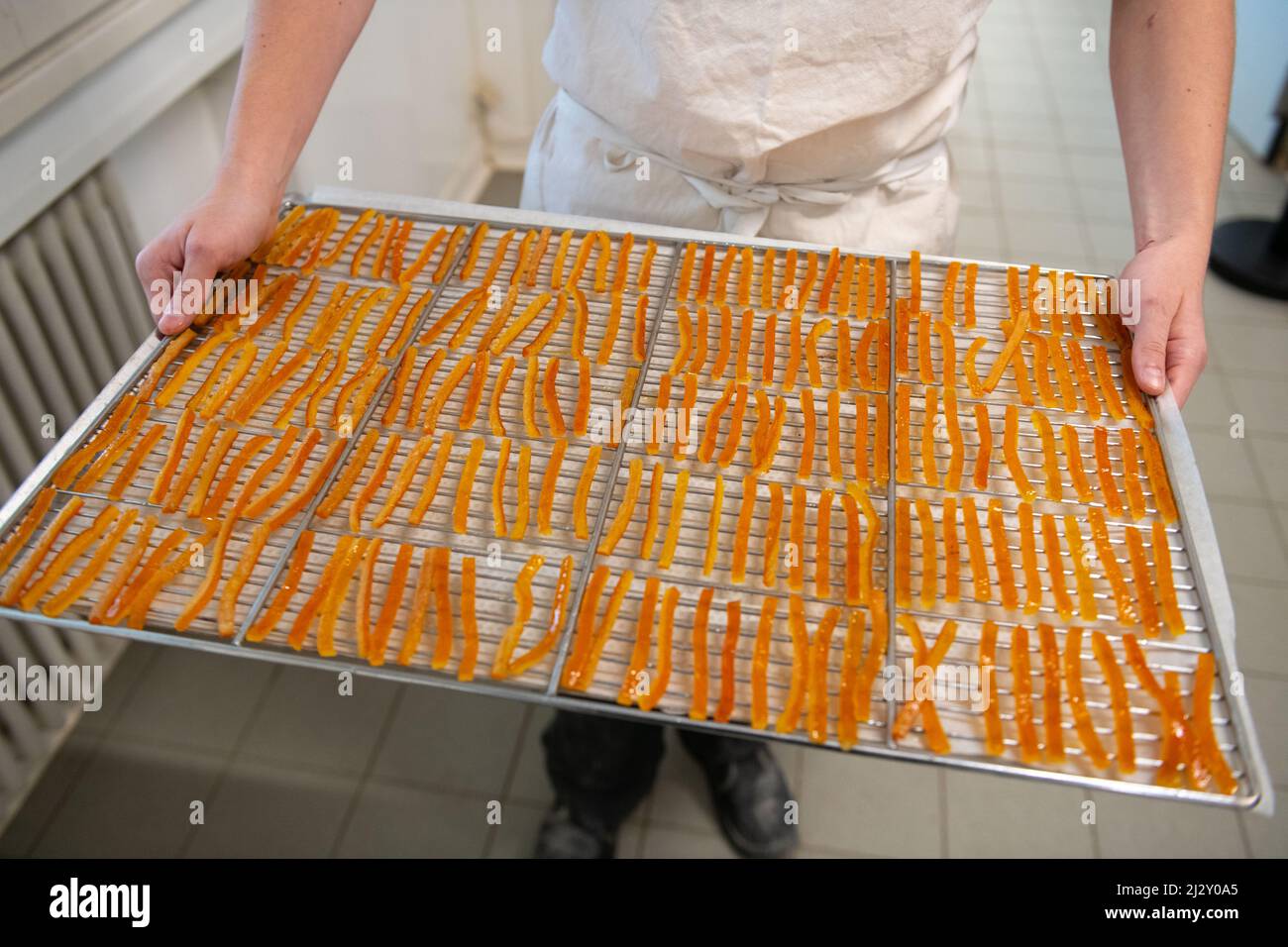 Cioccolato nella Chocolaterie Lionneton, fabbrica di cioccolato nel sud-est della Francia: Produzione di "orangette", batoni canditi di scorza d'arancia arrostiti in una tata Foto Stock